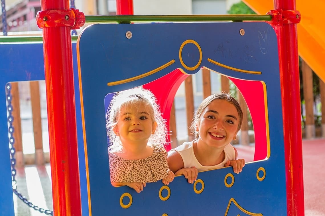 dues nenes mirant a través d' un rellotge de playground