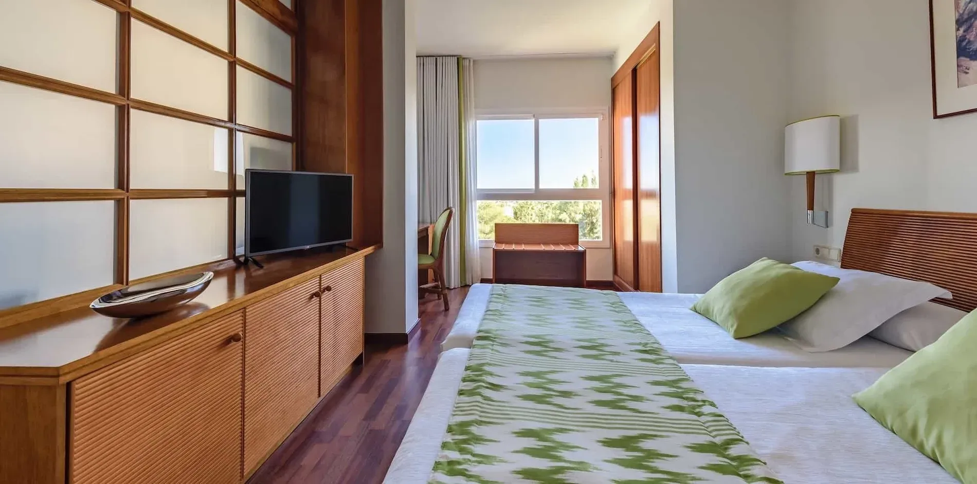 Gemütliches Doppelzimmer im Estival Park Silmar 4* Tarragona mit zwei Betten und grünen Akzenten. Offizielle Website.
