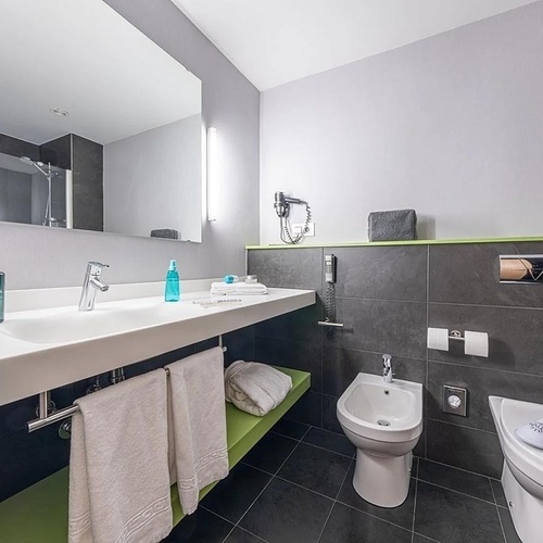 a bathroom with two sinks and a toilet with slippers on the floor