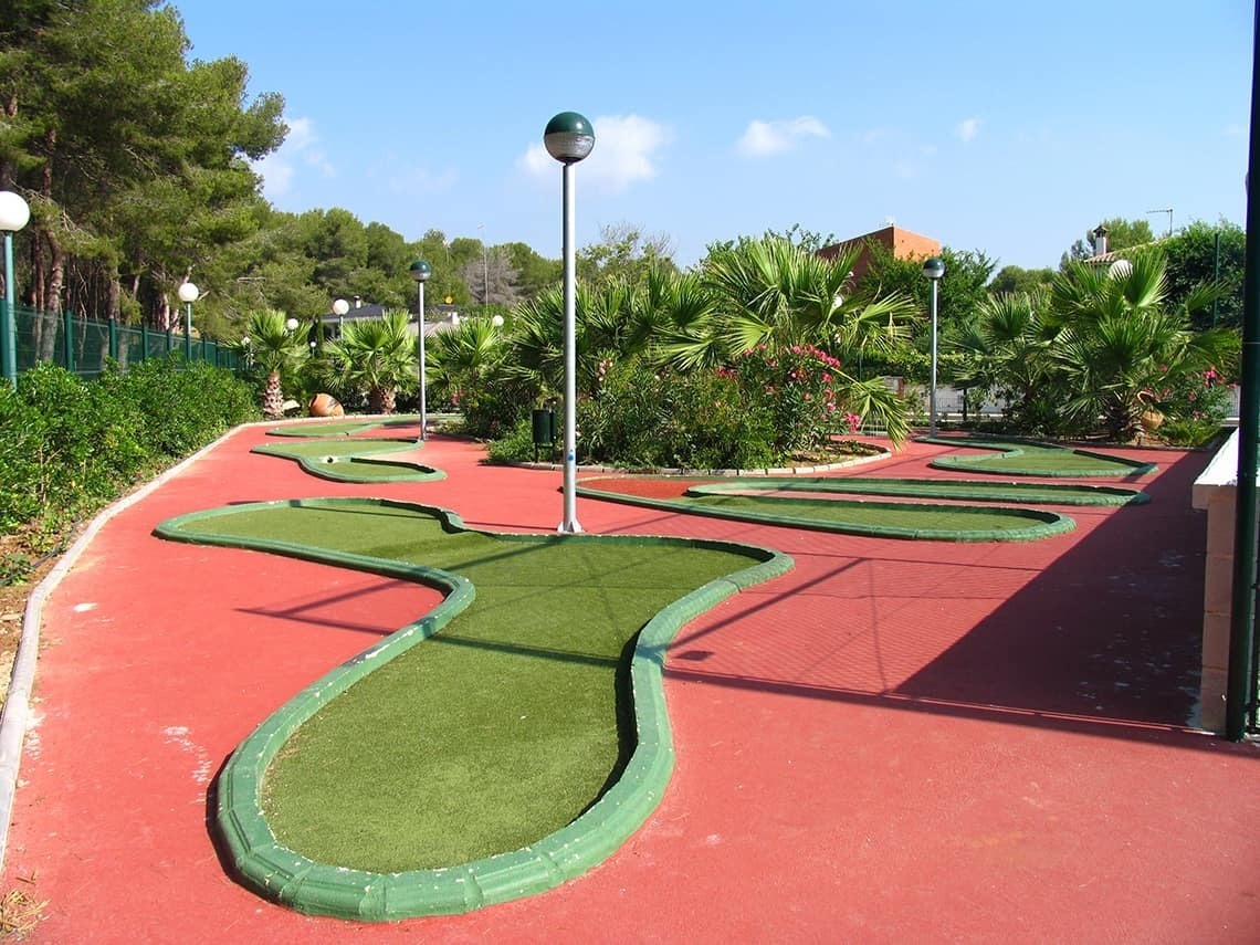 un campo de minigolf en un parque rodeado de árboles y flores