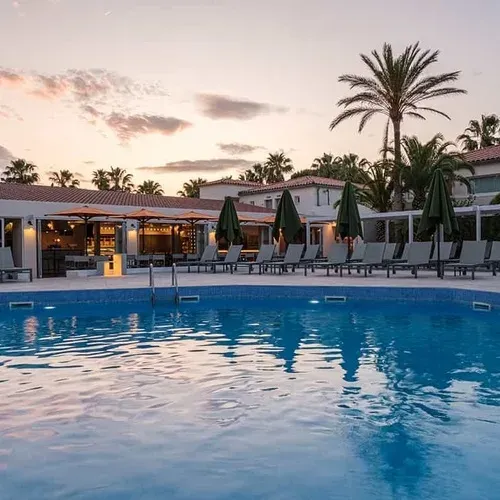 ESTIVAL: Corporate pool with loungers and palm trees at sunset.