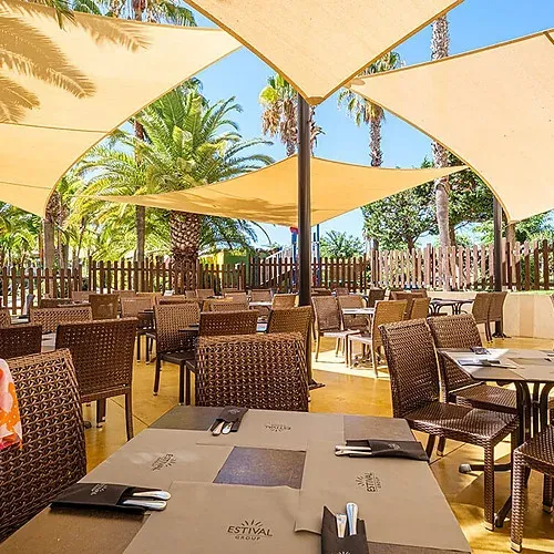 Outdoor dining at Estival Islantilla 4* Huelva: shaded tables, palm trees, relaxed atmosphere. Book now!