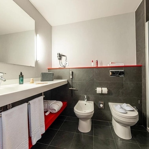 a bathroom with two toilets and a bidet