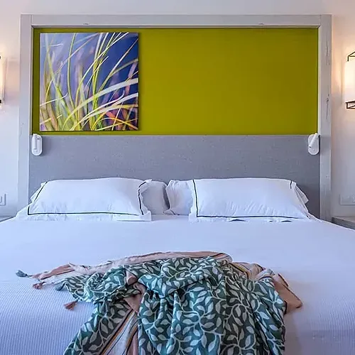 ESTIVAL: Corporate hotel room, double bed with decorative throw and abstract art.