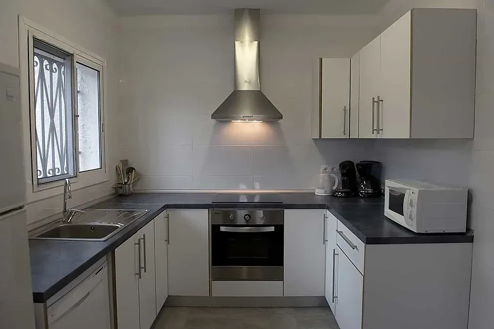 Cocina moderna ESTIVAL: Corporativa, equipada con electrodomésticos y encimera oscura.