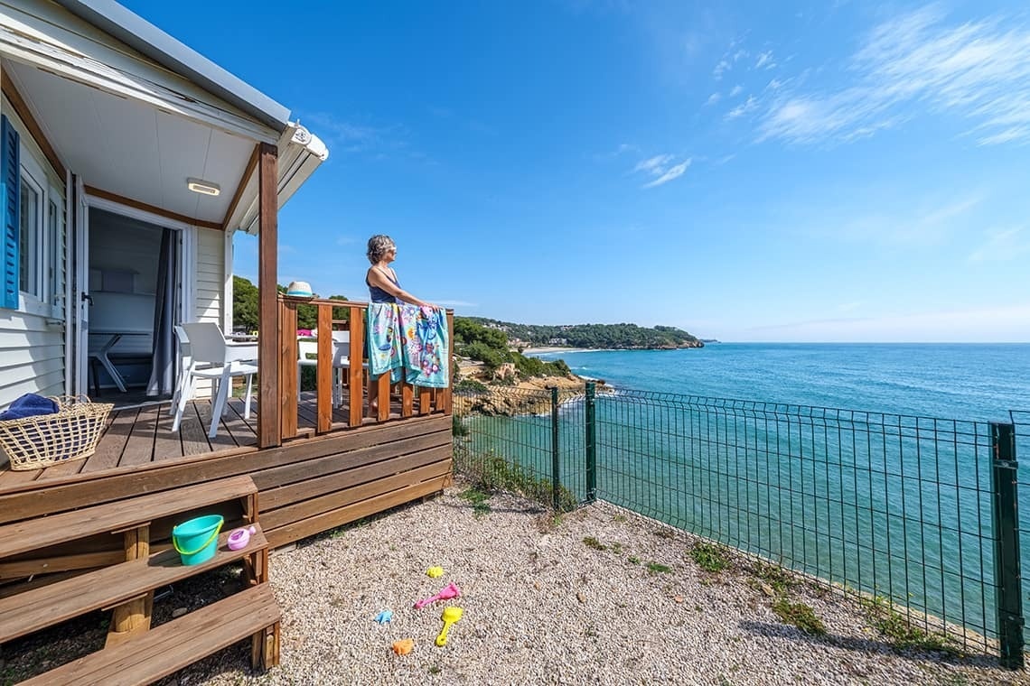 a woman stands on the deck of a mobile home overlooking the ocean