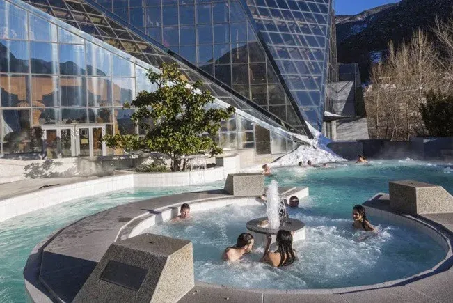 um grupo de pessoas estão a nadar numa piscina com uma fonte .