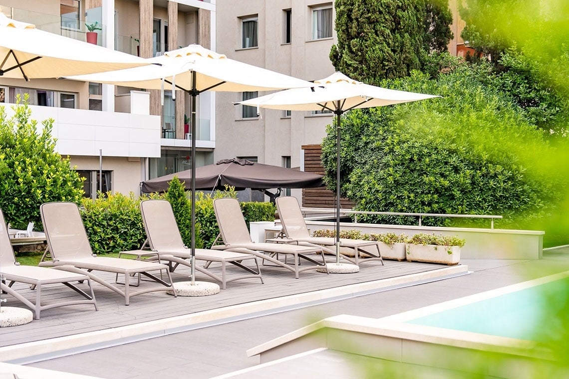 una piscina circondata da sedie e ombrelloni con un edificio sullo sfondo