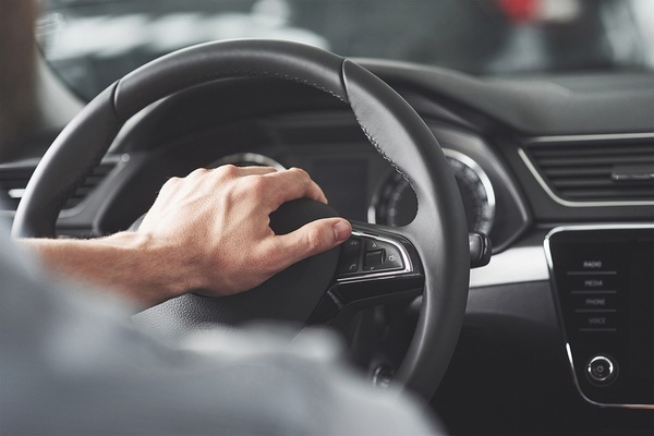 un hombre presiona un botón en el volante de un coche