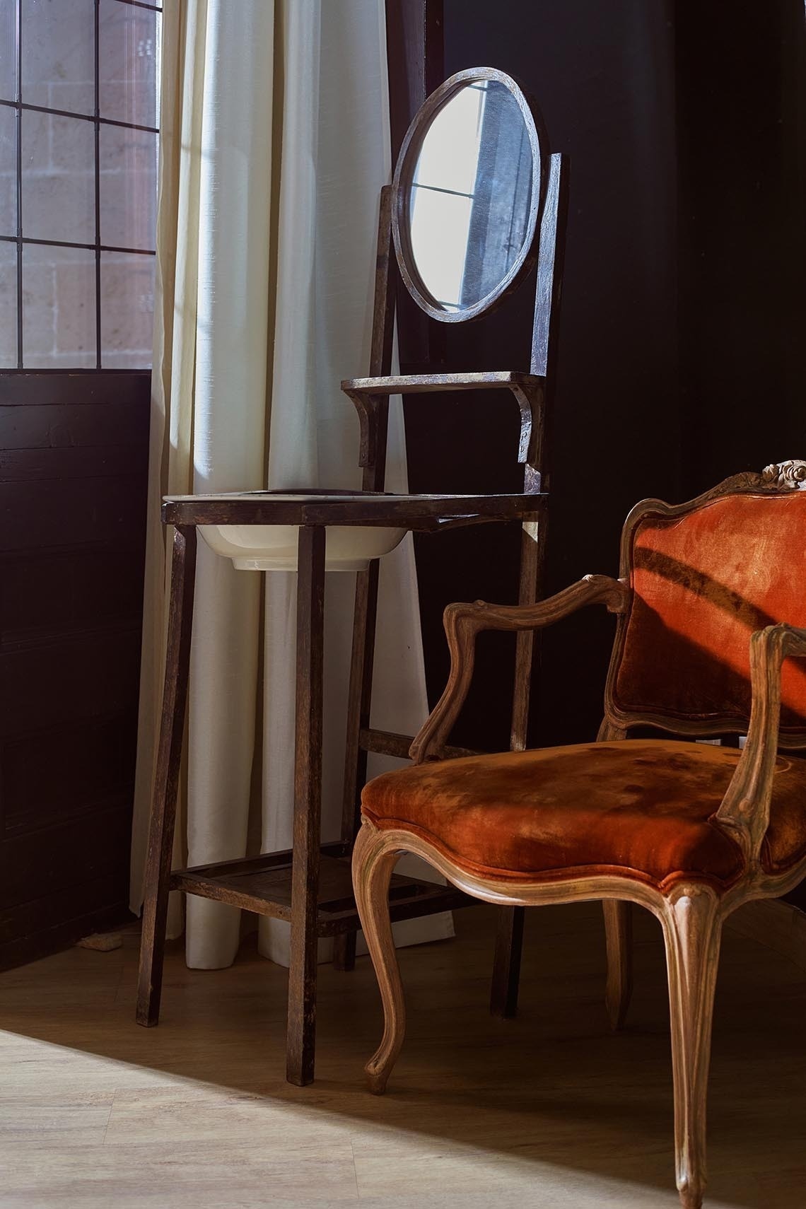 una silla roja está sentada junto a un lavabo y un espejo