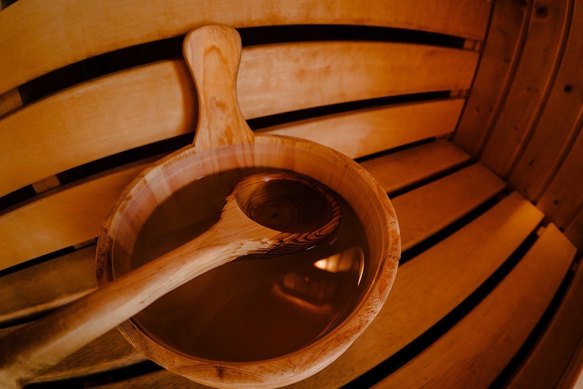 una sauna de madera con una puerta de vidrio y baldosas negras .