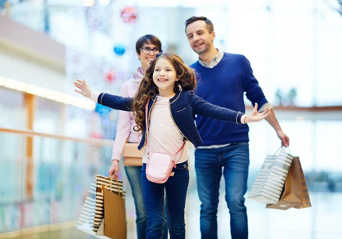 uma família caminha por um centro comercial com sacos de compras