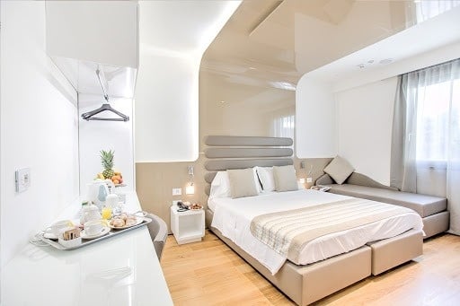 una camera d' albergo con un letto , un divano , un tavolo e un vassoio di cibo .