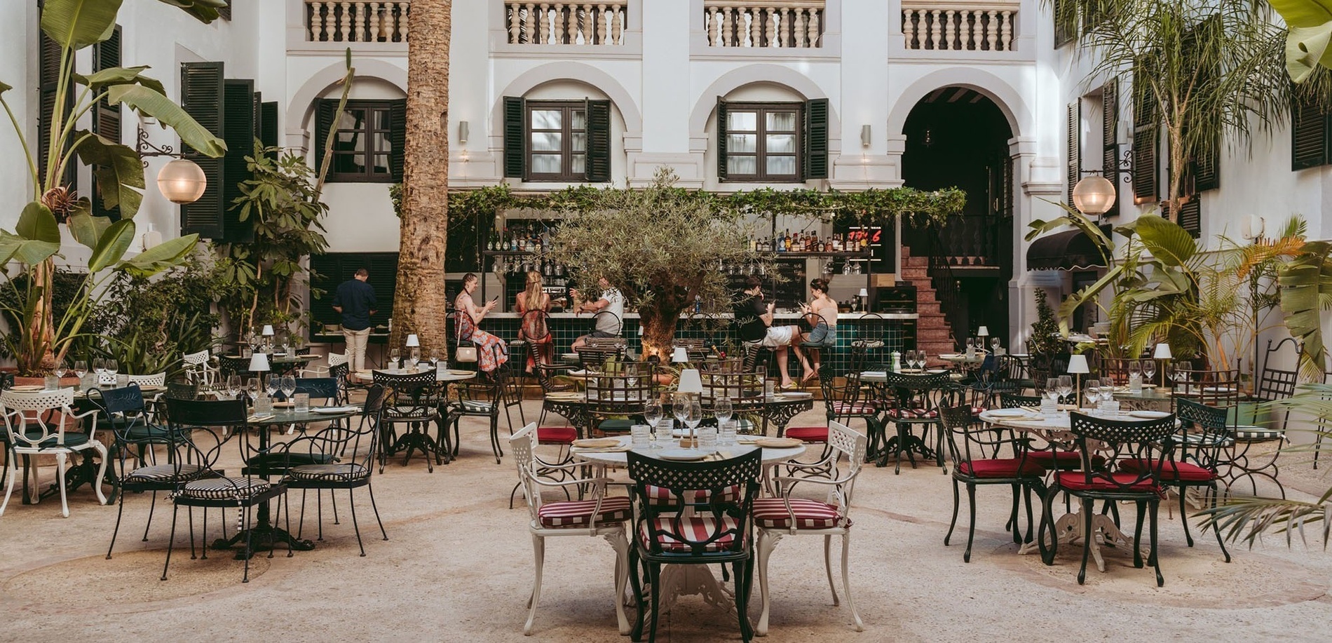 un restaurante lleno de mesas y sillas con un árbol en el medio