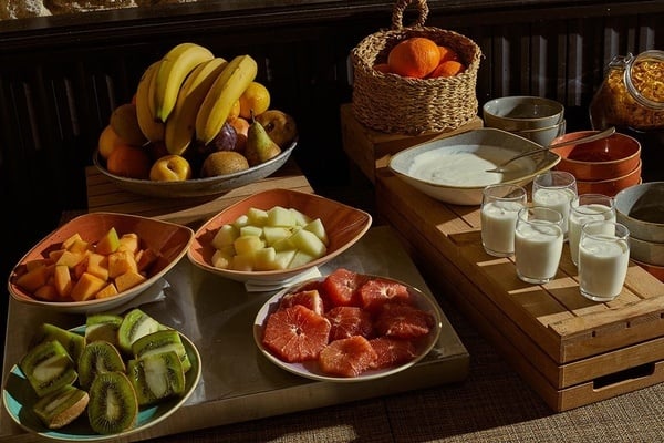 una mesa de madera llena de platos de frutas y vasos de leche