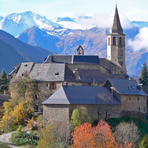 a small village with mountains in the background and a church in the foreground