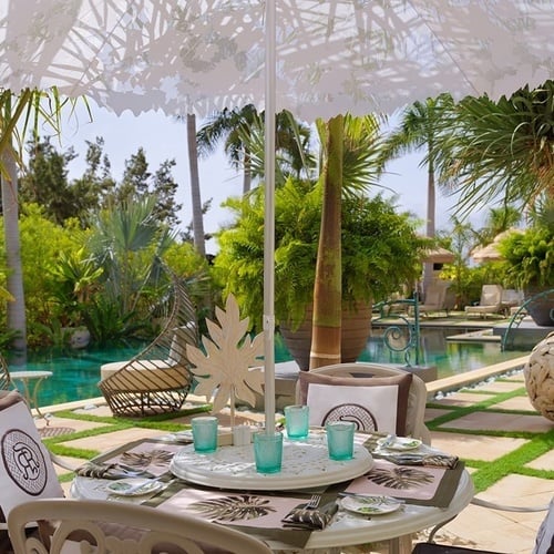 ein Tisch und Stühle unter einem weißen Regenschirm neben einem Pool