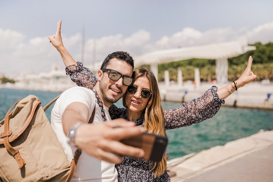 un hombre y una mujer toman un selfie con sus manos en el aire