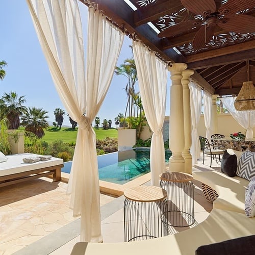 a patio with white curtains and a ceiling fan