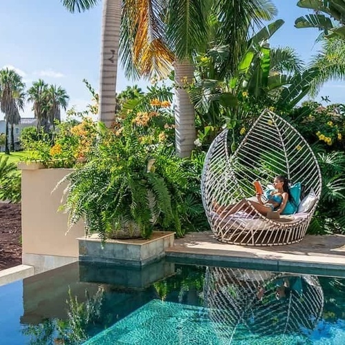eine Frau sitzt auf einem Stuhl neben einem Pool und liest ein Buch .