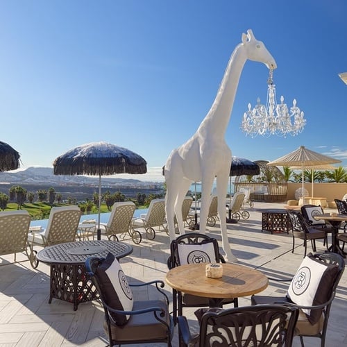 a statue of a giraffe is hanging from a chandelier on a patio