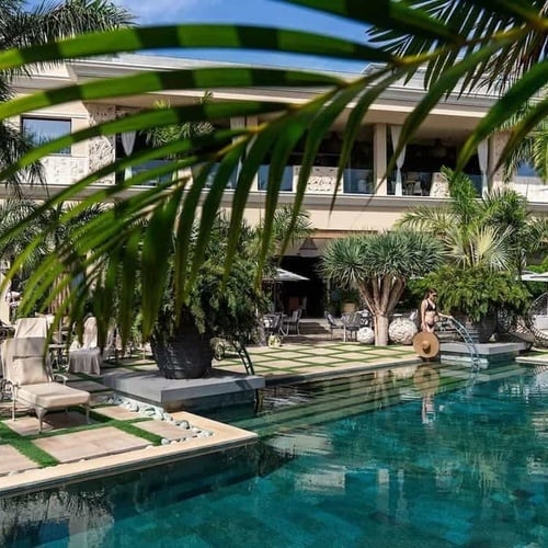 a large swimming pool is surrounded by palm trees
