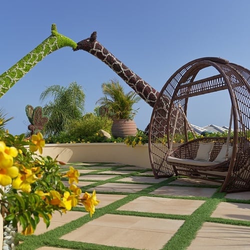 a wicker swing with a giraffe statue in the background