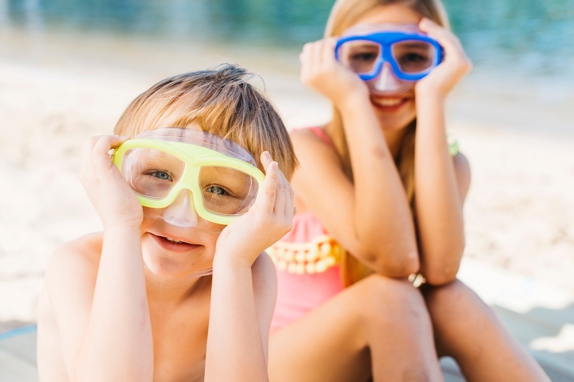 un niño y una niña con máscaras de buceo en la playa