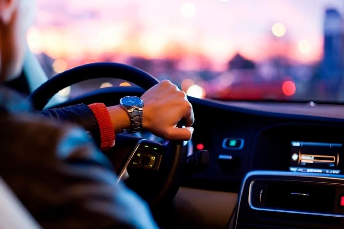 un hombre lleva un reloj mientras conduce un automóvil .