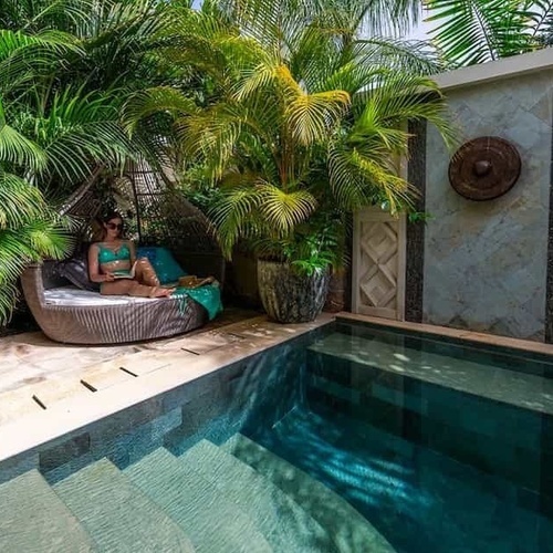 Eine Frau sitzt auf einem Stuhl neben einem kleinen Swimmingpool .
