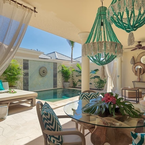 ein Wohnzimmer mit einem Tisch und Stühlen neben einem Pool