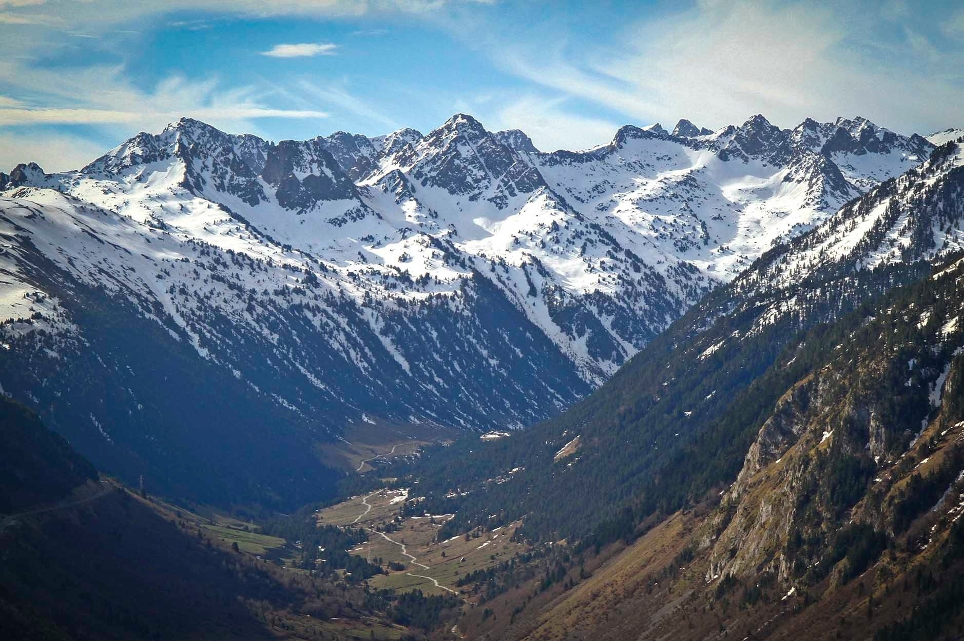 las montañas están cubiertas de nieve y hay un pequeño pueblo en el valle