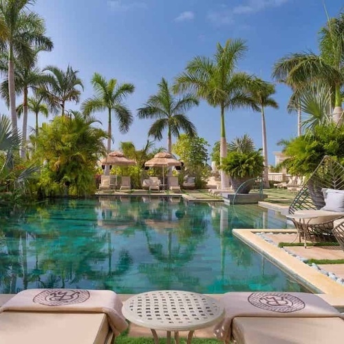 ein großer Swimmingpool umgeben von Palmen und Stühlen