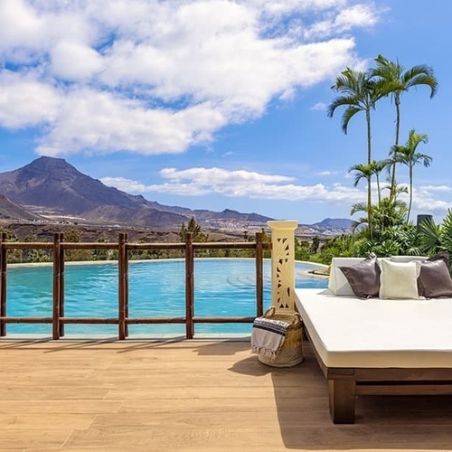 ein weißes Bett steht auf einem Deck neben einem Swimmingpool