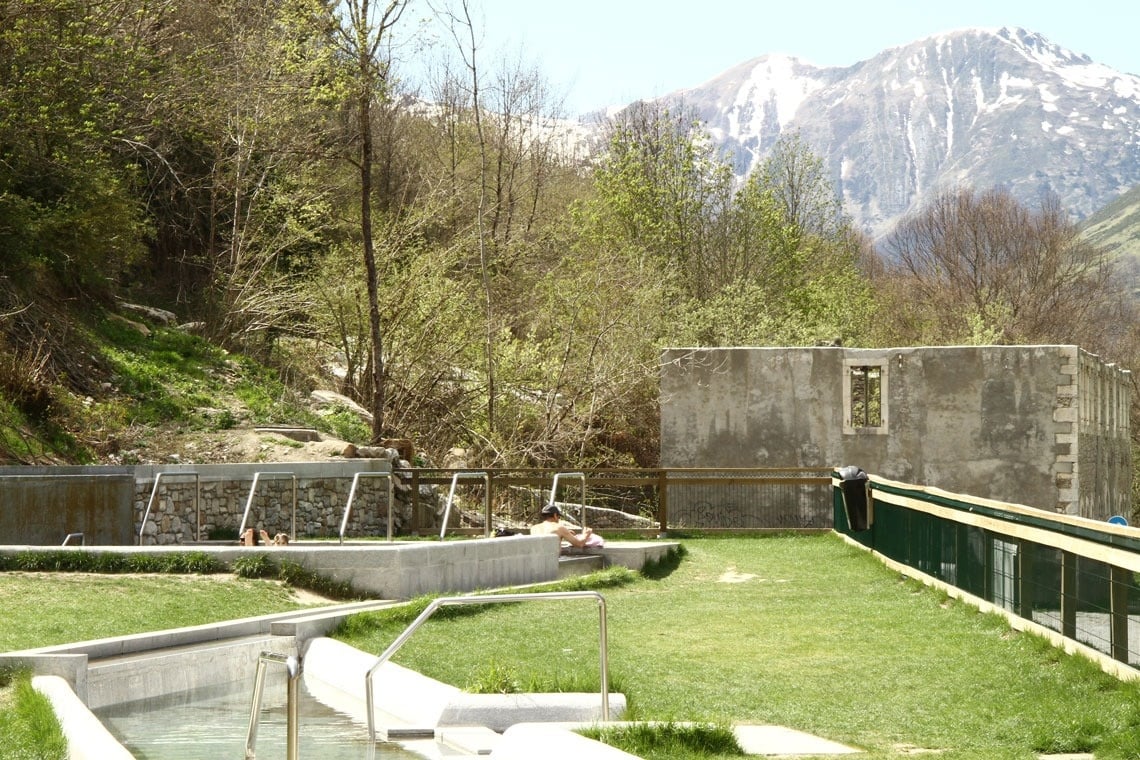 un homme se trouve dans une piscine avec des montagnes en arrière-plan
