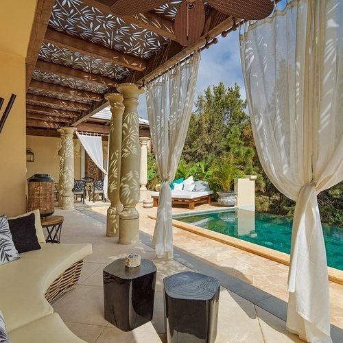 eine Terrasse mit weißen Vorhängen und einem Swimmingpool