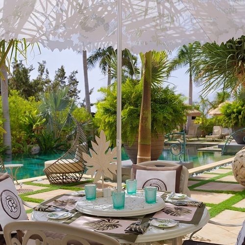 ein Tisch und Stühle unter einem weißen Regenschirm neben einem Pool