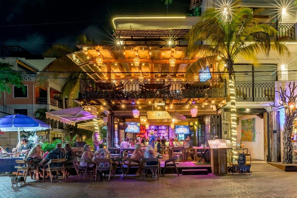 un grupo de personas se sienta en mesas frente a un restaurante llamado tigre