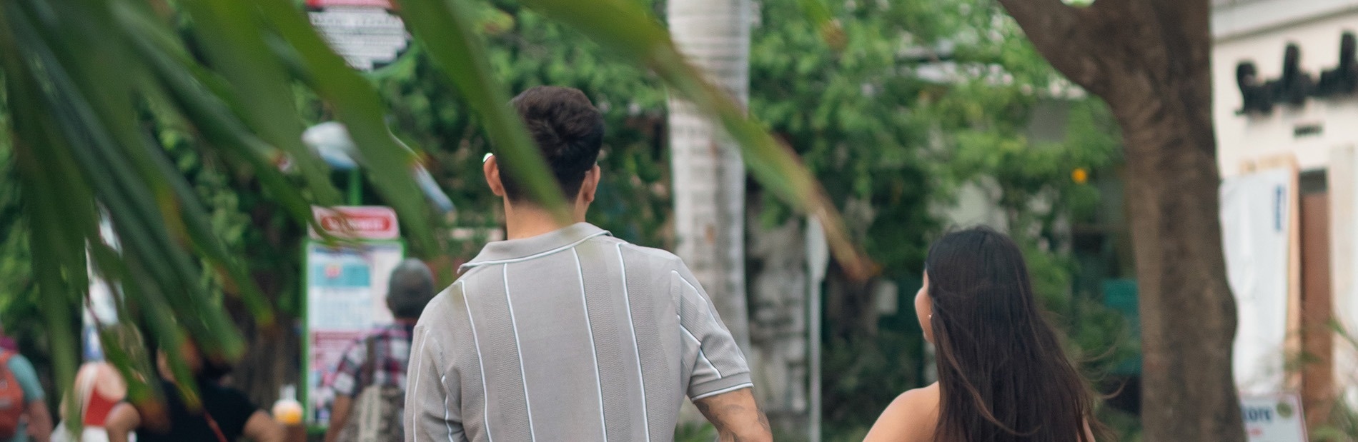 a man and a woman are walking down a street with a sign that says " bus stop "