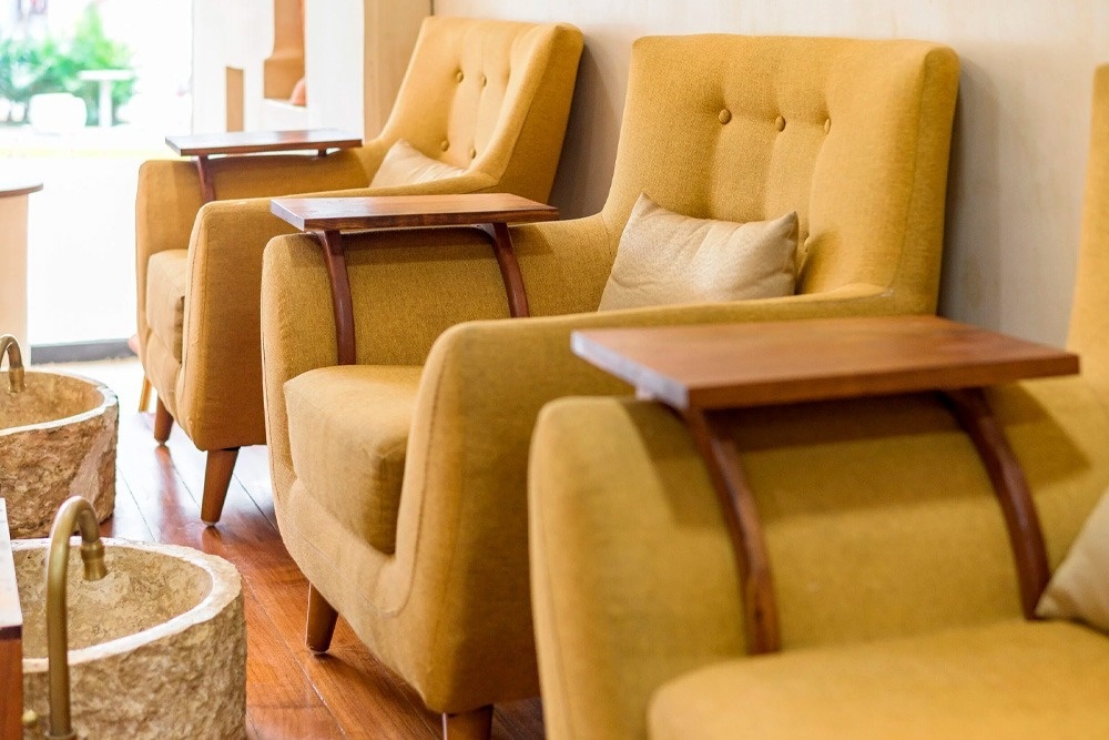 una fila de sillas amarillas con mesas de madera en los brazos