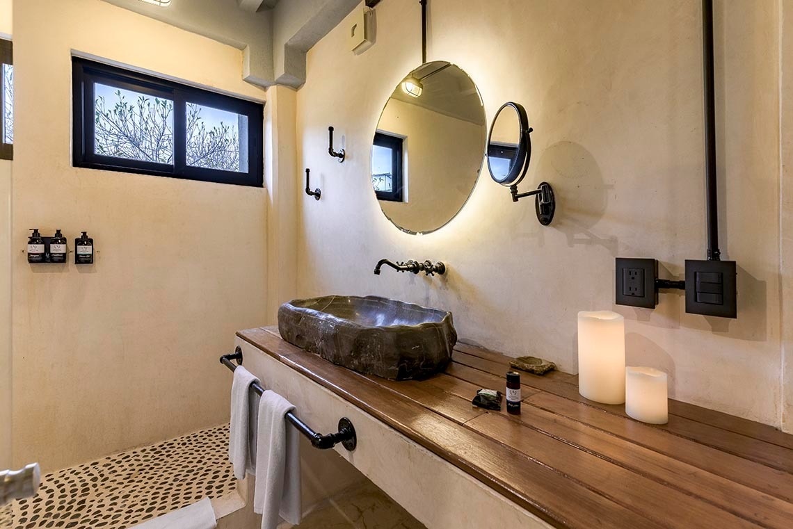 un baño con un lavabo de piedra y un espejo