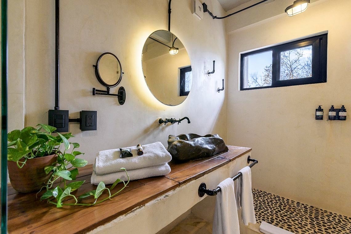 un baño con un lavabo y un espejo redondo