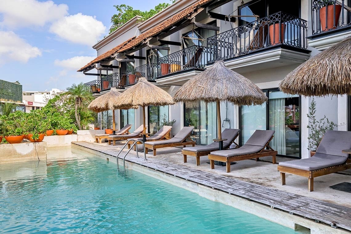 una piscina rodeada de sillas y sombrillas en un hotel