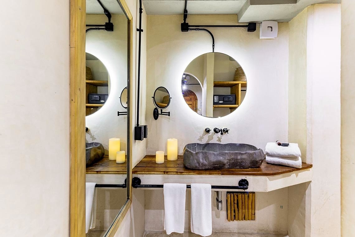 un baño con dos espejos y un lavabo de piedra