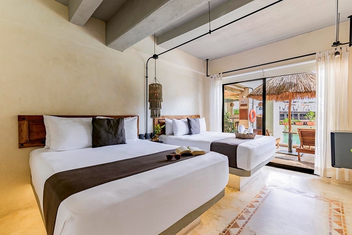 una habitación con dos camas y una puerta de vidrio que conduce a una terraza