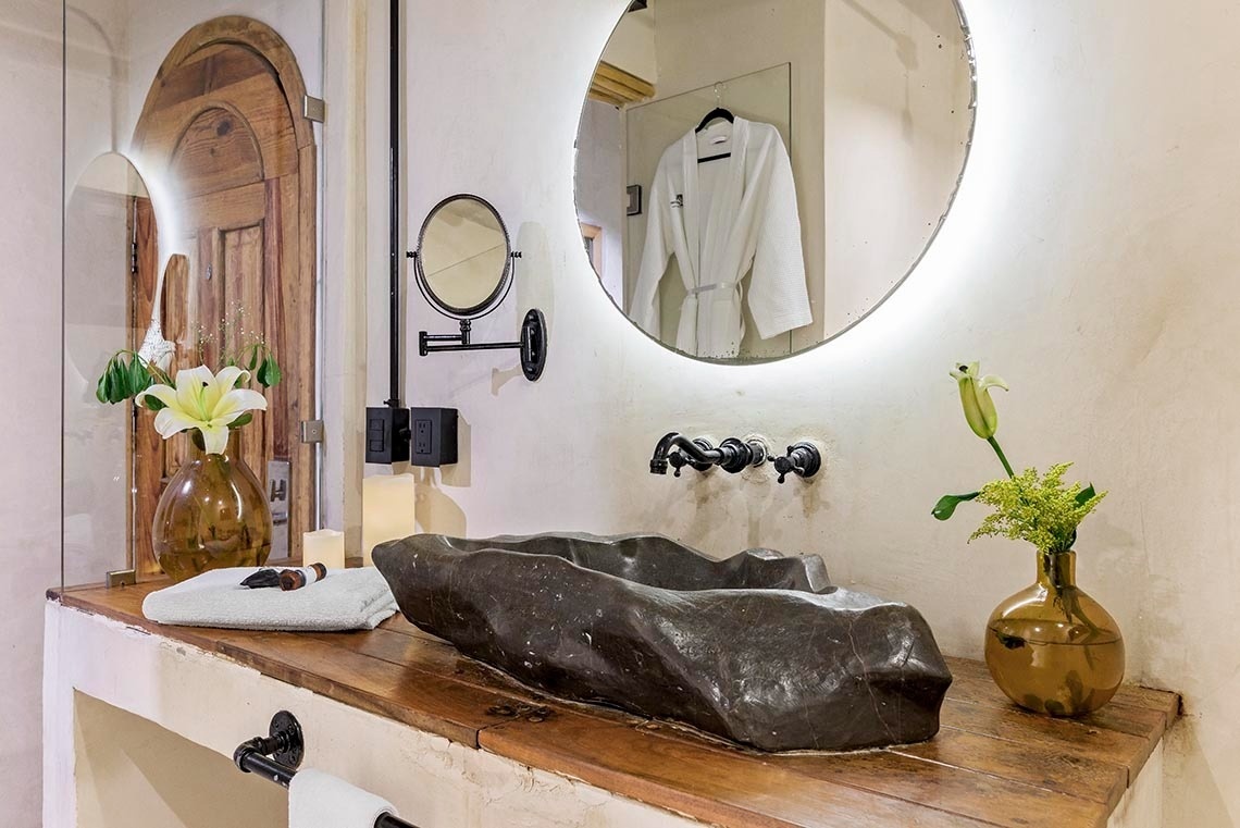 un baño con un lavabo y un espejo redondo