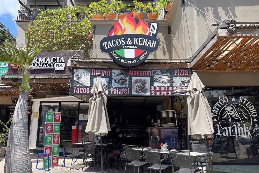 un grupo de personas se sienta en mesas frente a un restaurante llamado tigre