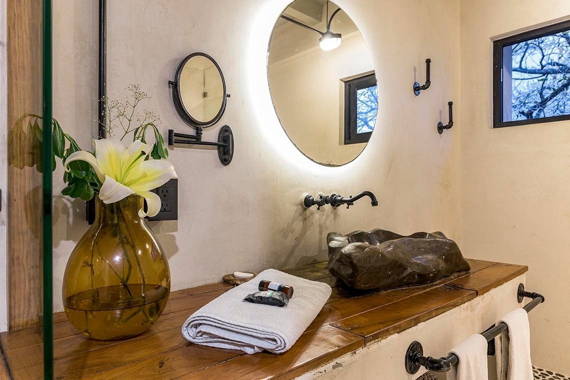 un baño con un lavabo y un espejo redondo