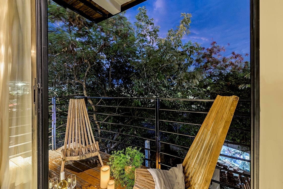 un balcón con una silla de madera y una botella de vino