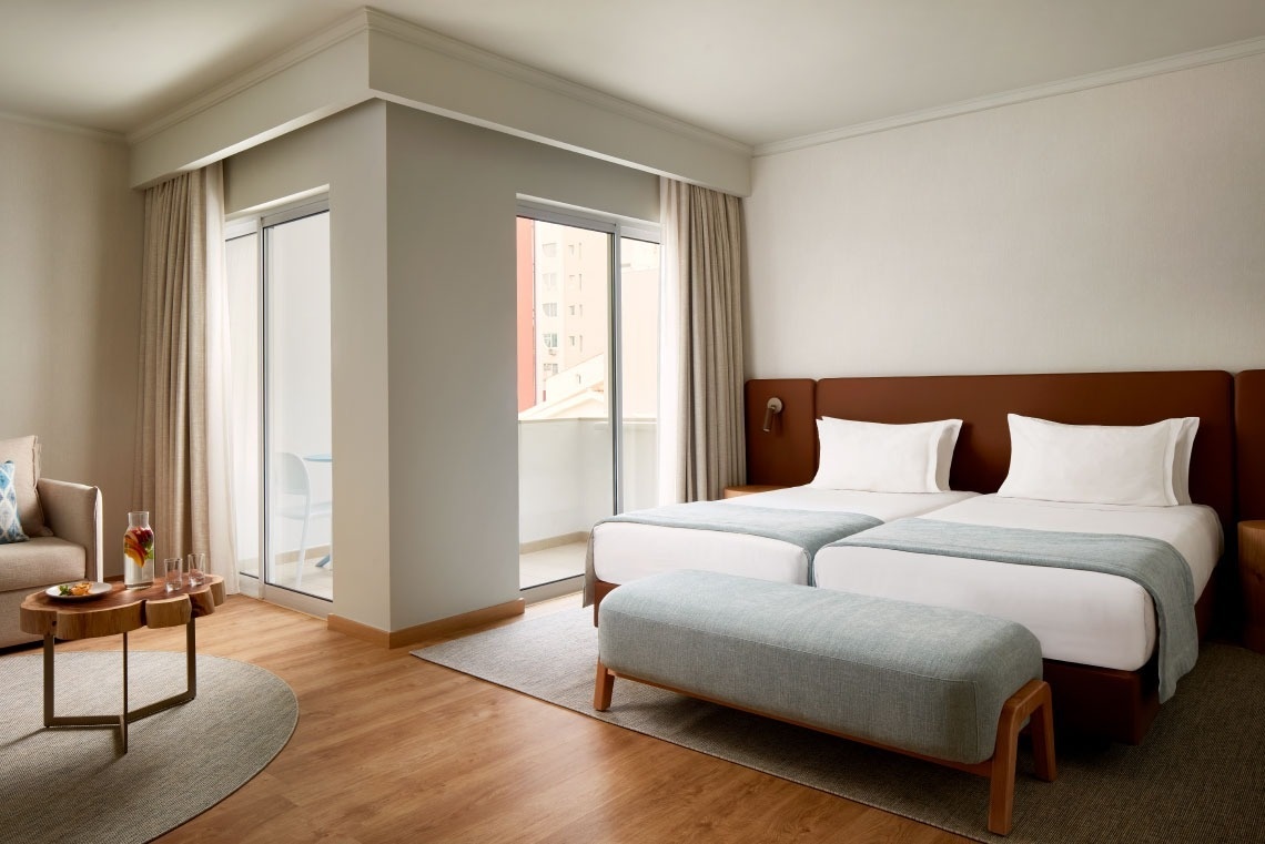 a hotel room with two beds and a sliding glass door